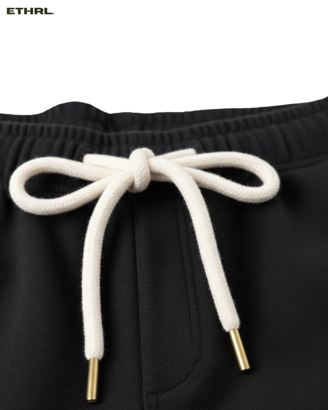 Black shorts with white drawstring and gold tips on a white background, featuring the brand 'ETHRL'.